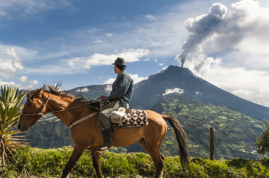 Unrecognizable farmer on a horse front of volcano Tungurahua Ecuador