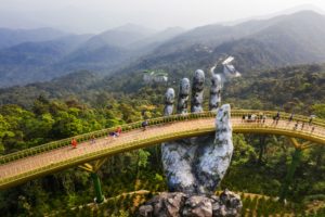 Top aerial view of the famous Golden Bridge is lifted by two giant hands in the tourist resort on Ba Na Hill in Danang, Vietnam.