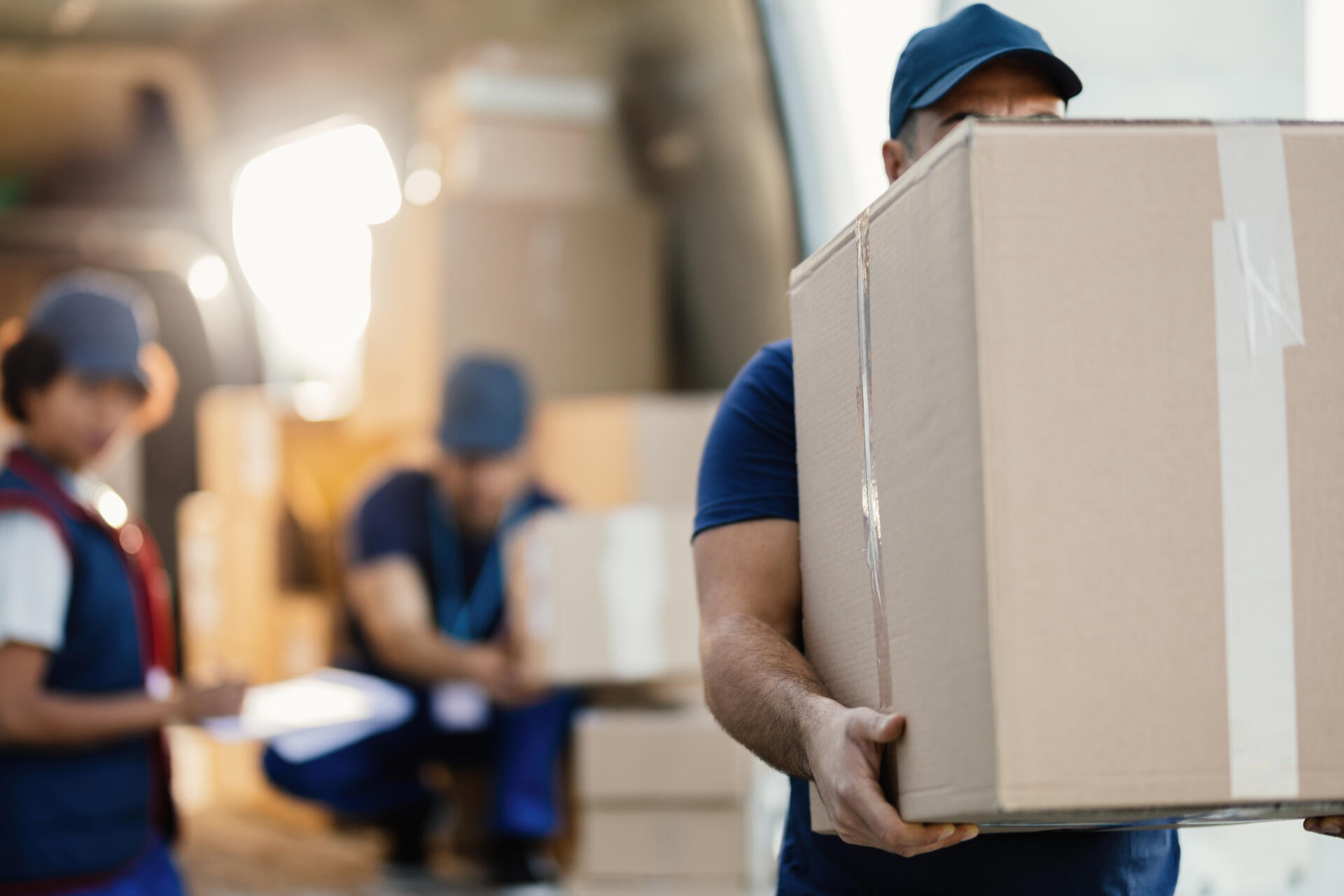 Delivery man unloading carboard boxes from a van.